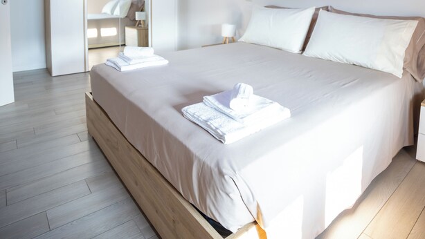 Une chambre avec un plafond en bois, un grand lit, une table de chevet et un miroir.