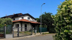 Une maison à deux étages, avec un toit recouvert de tuiles rouges, une entrée fermée par un portail et un lampadaire.