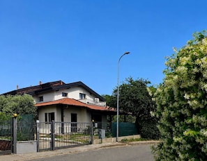 Ein zweistöckiges Haus mit rotem Ziegeldach, einem Vorgeländer und einer Straßenlaterne.