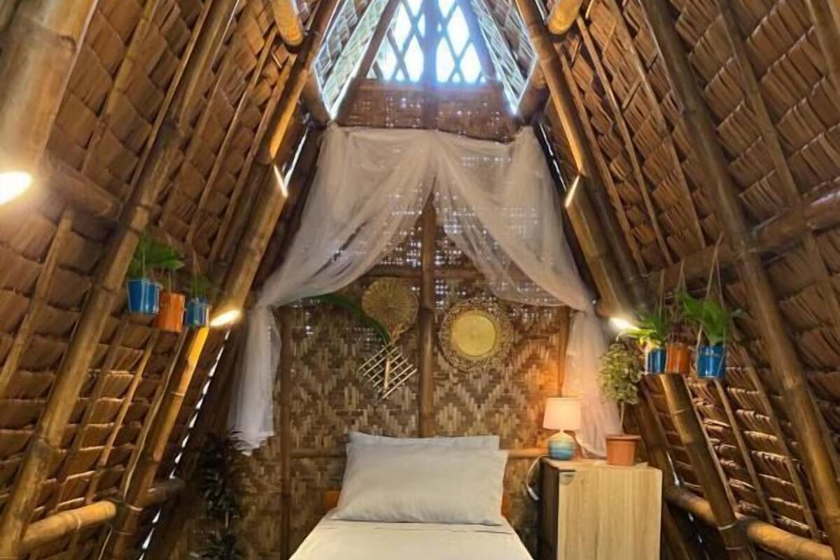 A room with a bed, a nightstand, a lamp, and a window with a view.