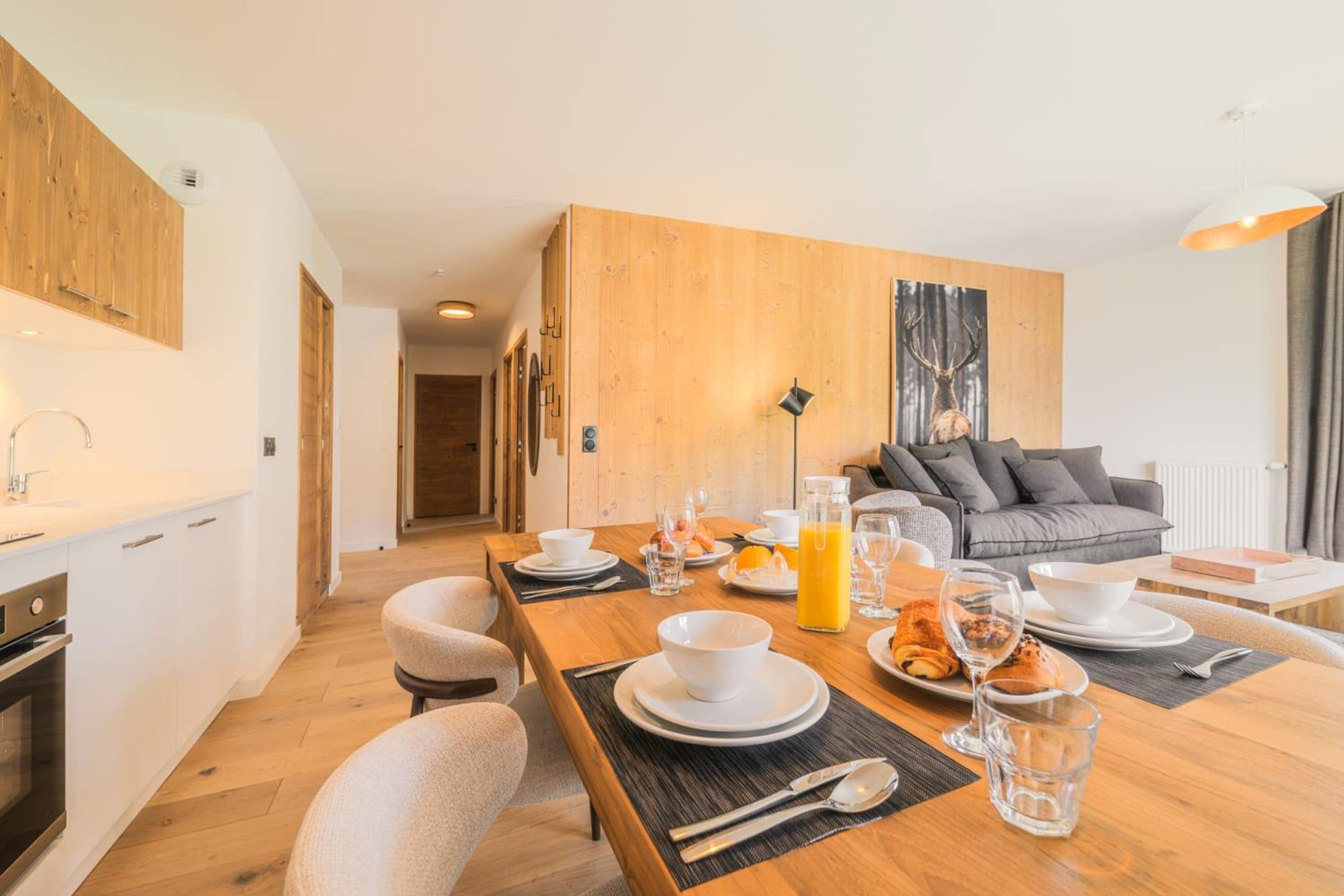 Una cocina moderna con comedor, pared de madera y sofá gris.
