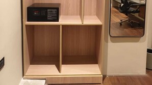 Una habitación con un armario de madera, un escritorio, una silla y un espejo en la pared.
