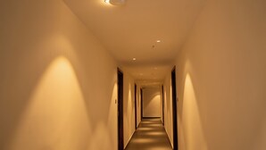A long, narrow hallway with a carpeted floor and walls painted in a light color. - Hotel Vdara Bliss (Vijayawada)