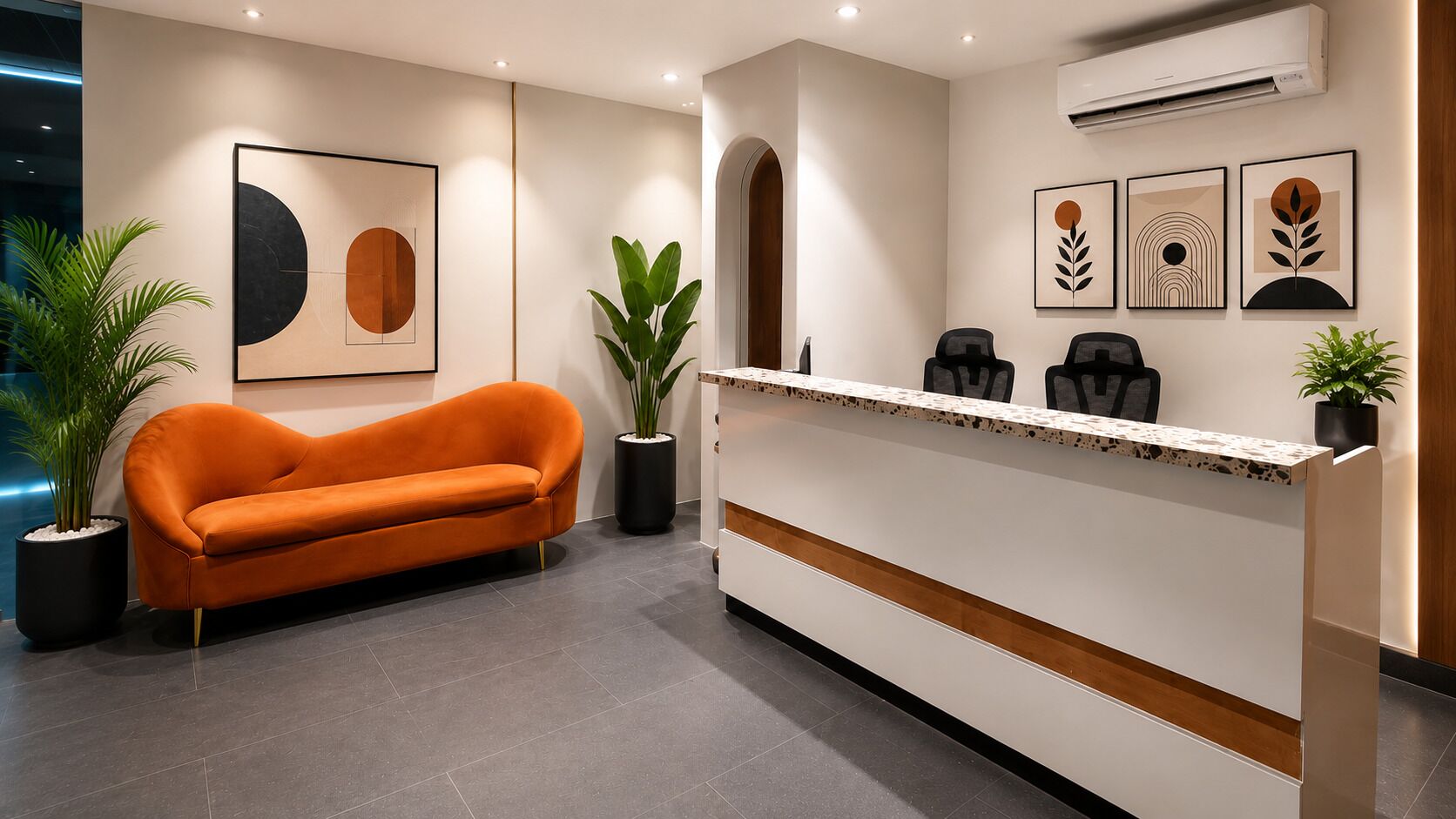 Un espace d’accueil avec un canapé, un comptoir de réception et des œuvres d’art encadrées accrochées au mur.