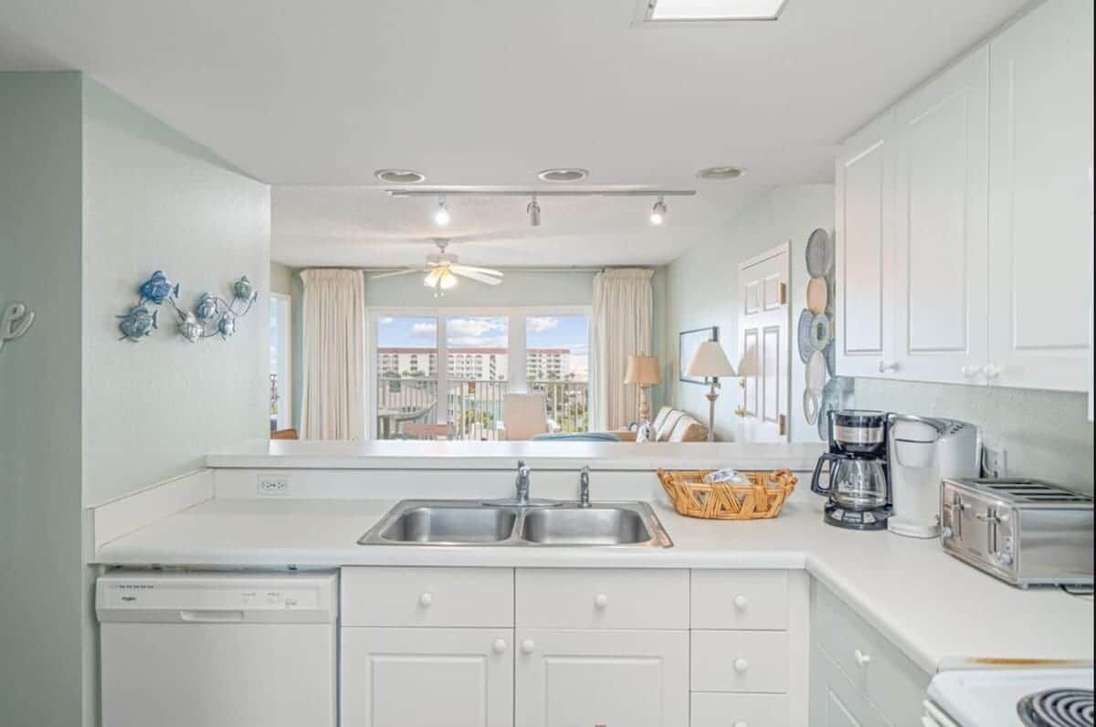 A modern kitchen with a dishwasher, double sink, and a coffee maker.
