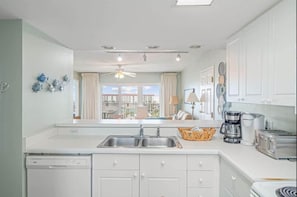 A modern kitchen with a dishwasher, double sink, and a coffee maker. - 2/2 Ocean front/view, heated pool, snowbird ready (Fort Walton Beach)