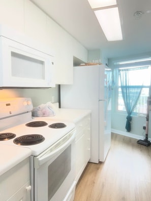 Une cuisine avec des appareils électroménagers blancs, notamment un four à micro-ondes, une cuisinière et un réfrigérateur.