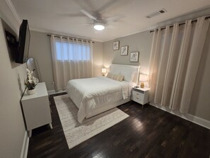A bedroom with a bed, bedside tables, a nightstand, a ceiling fan, a flat-screen TV, and a window with curtains. - Updated 3bd/2ba house near 6 flags and downtown Atlanta (Mableton)
