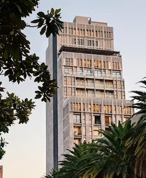 Ein mehrstöckiges Gebäude mit modernem architektonischen Design, das eine Reihe von Balkonen und großen Fenstern aufweist.