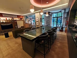 Eine moderne Bar mit einer langen Theke, Barhocker und einer Sitzecke mit einer Couch und Sesseln.