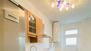 Une cuisine moderne avec des meubles en bois, un réfrigérateur en acier inoxydable, un four encastré et une fenêtre qui laisse entrer la lumière naturelle.