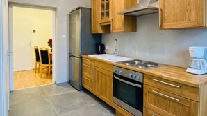 Une cuisine compacte dotée de meubles en bois, d’un réfrigérateur en acier inoxydable, d’un four encastré et d’une cuisinière à gaz.