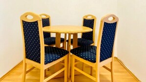 Un petit coin repas avec une table ronde en bois et quatre chaises recouvertes d’un tissu bleu.