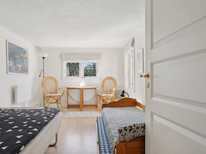 A room with two beds, a small table, two wicker chairs, a window, and a door. - 5 Star Holiday Home in Vejby (Vejby)