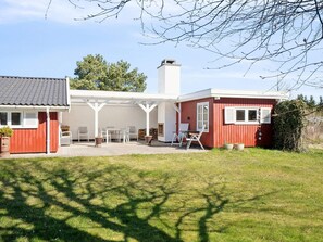Punavalkoinen talo, jossa on terassi, ulkotila istumiseen ja savupiippu.