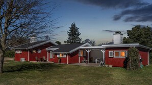 Ein rotes, zweistöckiges Haus mit einer überdachten Veranda und einem Schornstein.