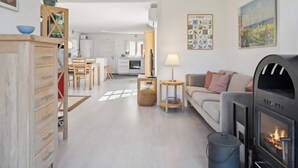 Ein modernes Wohnzimmer mit Kamin, einem Essbereich und einer Küche im Hintergrund.