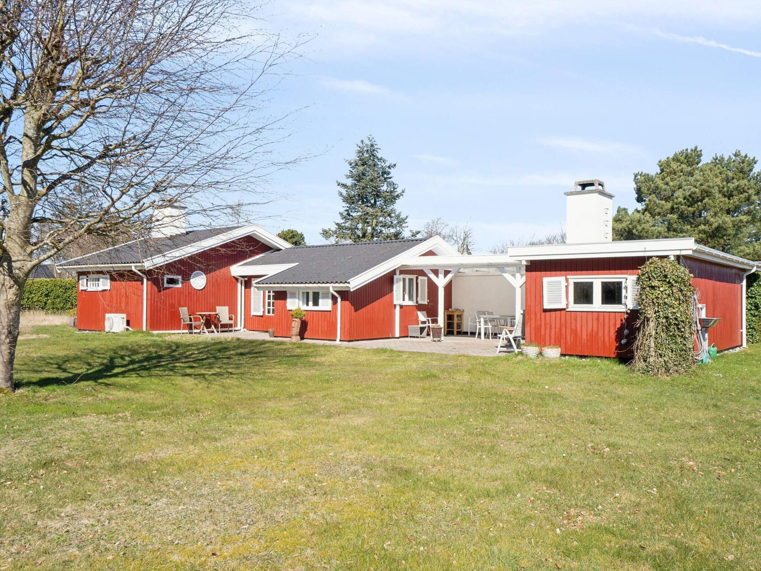 A red building with a covered patio area, a chimney, and a lawn.