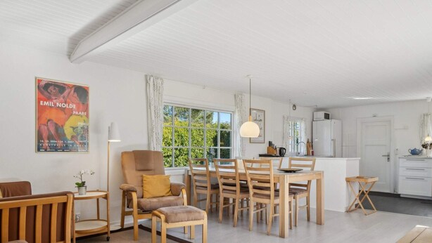 Ein modernes Wohnzimmer mit Essbereich, Küche und einem großen Fenster für natürliches Licht.