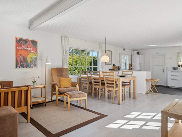 A modern living space with a dining area, kitchen, and a large window providing natural light. - 5 Star Holiday Home in Vejby (Vejby)