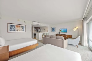 Ein Hotelzimmer mit Bett, Sofa, Fernseher und Küchenzeile.