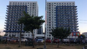 Dois edifícios residenciais altos com varandas, uma placa de estacionamento e um poste de luz.