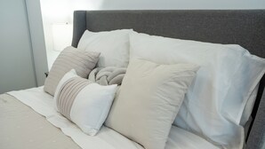 Ein Bett mit vielen Kissen und einem grauen Kopfteil.