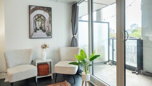 Ein modernes Wohnzimmer mit großem Fenster, einem gerahmten Bild an der Wand und einer Topfpflanze.