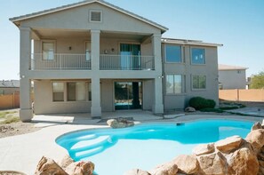 Ein zweistöckiges Haus mit Swimmingpool, Balkon und Garage.