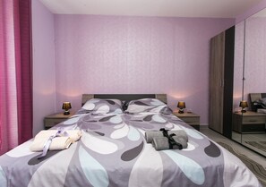 Ein Hotelzimmer mit einem Bett, Nachttischen, Lampen, einem Kleiderschrank und einem Spiegel.