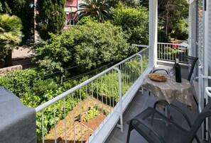 Ein Balkon mit Esstisch, Stuhl und einer Topfpflanze.