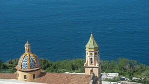 A coastal view with a building featuring a dome and a bell tower. - House Salú Suite (Praiano)