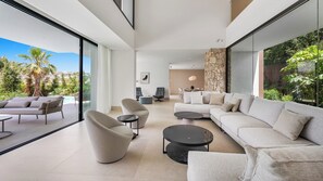 A modern living room with a large sectional sofa, a round coffee table, and a dining area with a table and chairs. - Villa The Address by Vacation Marbella (Marbella)