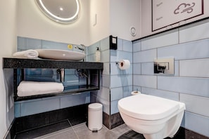 Et moderne badeværelse med vask, toilet og skraldespand.