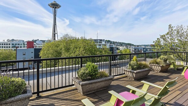 Terraza con mobiliario exterior, vista de la Space Needle y edificios circundantes.