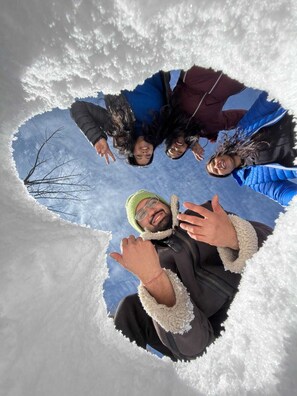 A group of people in a heart-shaped arrangement on snow.