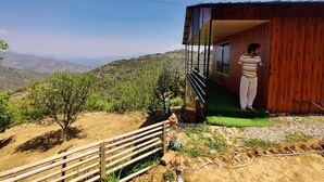 A wooden cabin with a balcony overlooking a mountainous landscape. - Kanatal Greenhood Resort (Kanatal)