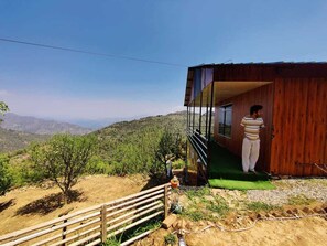 A wooden cabin with a balcony overlooking a mountainous landscape.