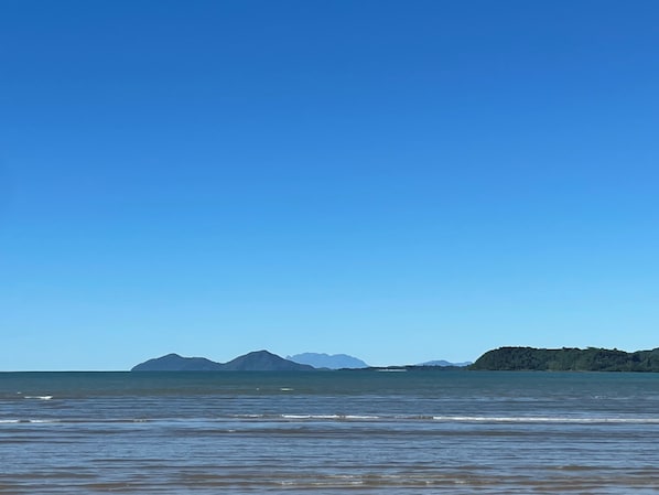 A beach with calm waters and distant mountains.