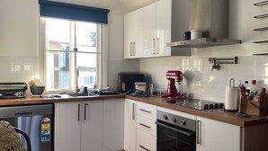 Eine Küche mit weißen Schränken, einem roten Mixer, einem Toaster und einem Backofen.