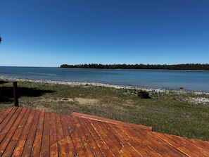 A wooden deck leading to a lake with a forest in the background.