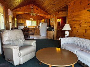 A log cabin interior with a living room, a dining area, and a kitchen. - Drummond Island Hotel & Vacation Homes - Kaye's Little Cabin (Drummond)