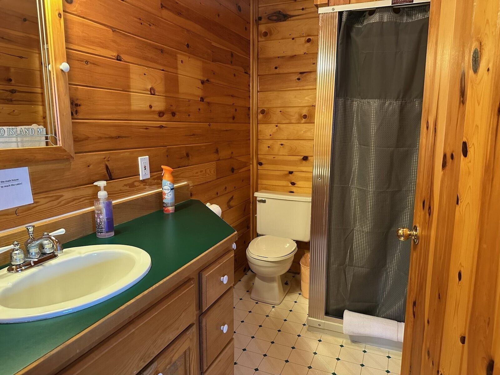 A wooden cabin bathroom with a sink, toilet, and shower.