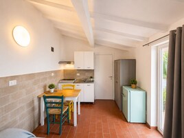 A compact kitchen with white cabinets, a small refrigerator, and a dining area with a table and chairs.