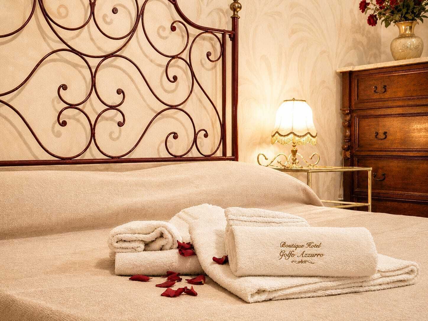 Una cama bien hecha con un cabecero decorativo, una lámpara de noche y un aparador de madera con cajones.