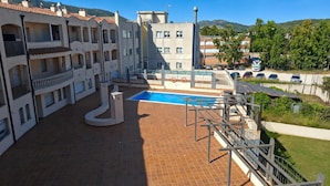 Ein Wohngebäude mit Schwimmbad, Balkonen und Blick auf die Umgebung.