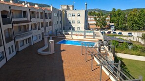 Ein Wohngebäude mit Schwimmbad, Balkonen und Blick auf die Umgebung.