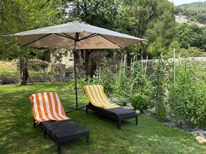 Ein Sitzbereich im Freien mit zwei Liegestühlen und einem großen Sonnenschirm.