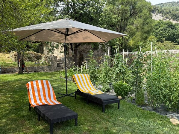 An outdoor seating area with two lounge chairs and a large umbrella.