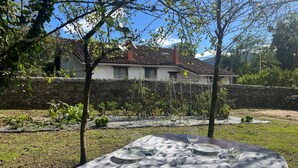 Un espace de restauration en plein air avec une table dressée pour quatre personnes, entouré d’un mur de pierre et de verdure.